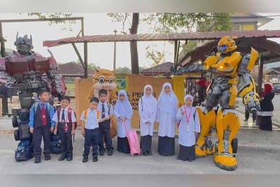 Murid-murid SK Kuala Perai bergambar bersama maskot Sang Kancil, Bumblebee dan Optimus Prime yang berada di hadapan sekolah pada hari pertama persekolahan pada Isnin.
