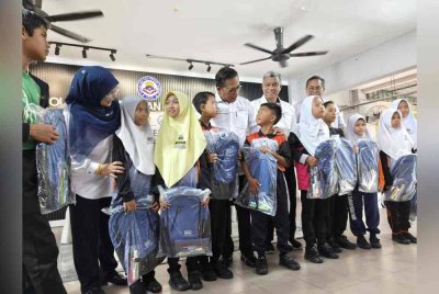 Azman (tengah) beramah mesra dengan murid yang menerima kit persekolahan pada Program Bantuan Satu Juta Buku Tulis Kitar Semula kepada murid B40 pada Isnin.