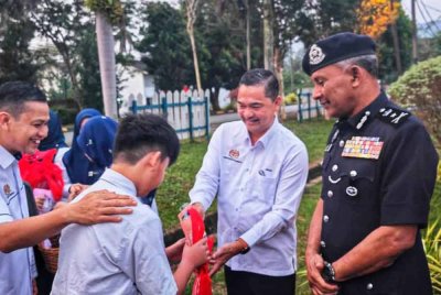 Mohamad Noor (kanan) ketika menyantuni pelajar yang hadir sempena program First Day at School di SMK Felda Lurah Bilut, Bentong pada Isnin.