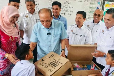 Wan Rosdy (dua dari kiri) menyerahkan kit peralatan sekolah kepada murid Tahun 1 di SK Janda Baik pada Isnin.