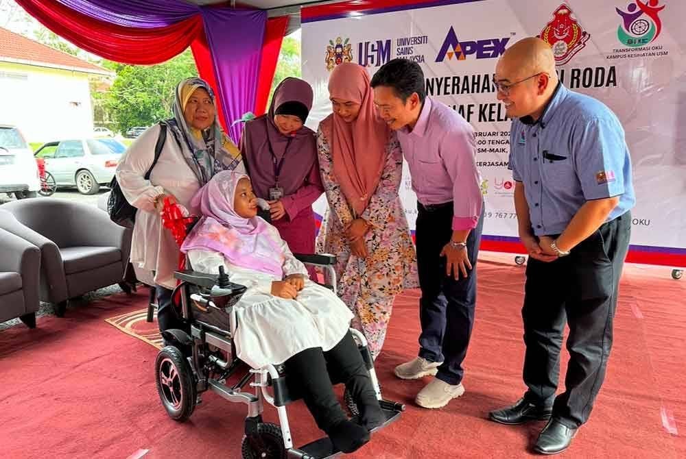 Puteri Aisyah yang berkerusi roda menerima bantuan peralatan kemudahan itu yang disampaikan oleh Siti Farahida (tiga dari kanan sambil diiringi Dr Wan Rosli (dua dari kanan).