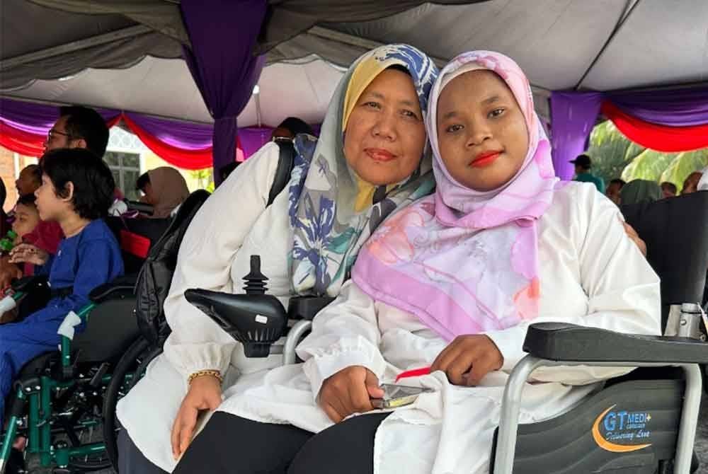 Puteri Aisyah (kanan) ditemani Aziah (kiri) hadir bagi menerima sumbangan kerusi roda.