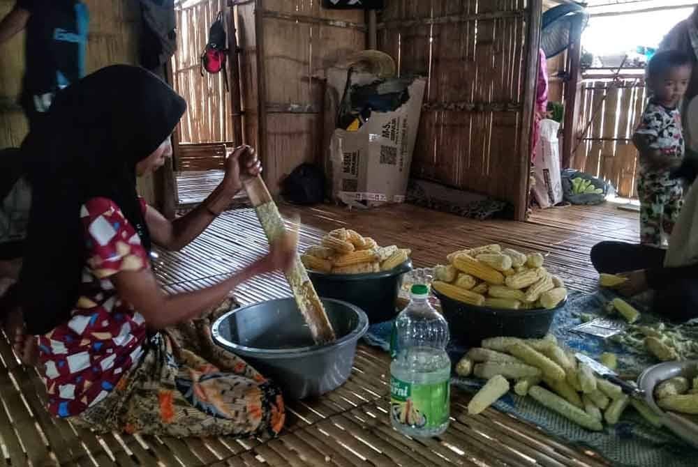 Wak Dui memasukkan butir jagung ke dalam buluh sebelum dimasak. Foto ihsan orang awam