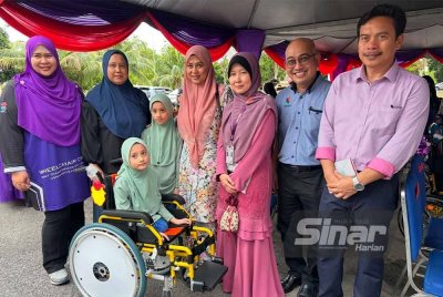 Mohd Zulkifli (dua dari kanan) mengiringi Siti Farahida (empat dari kanan) menyampaikan kerusi roda yang dimodifikasi kepada penerima.