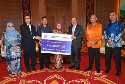 Hajiji (tiga dari kiri) menerima replika cek RM300,000 bantuan kepada Sabah oleh YKN dan disaksikan Nancy (tengah) pada majlis penyerahan di Menara Kinabalu, Kota Kinabalu.