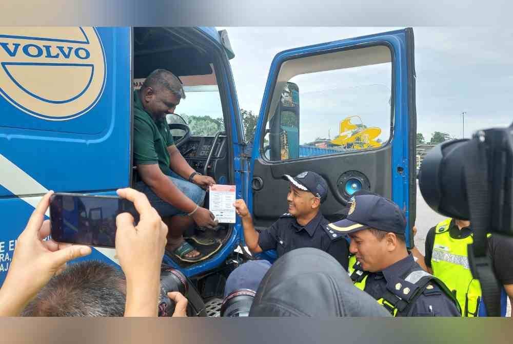 Mohd Yusof memberi risalah larangan pergerakan kepada salah seorang pemandu kenderaan berat di R&R Dengkil Arah Utara, Selangor pada Rabu.