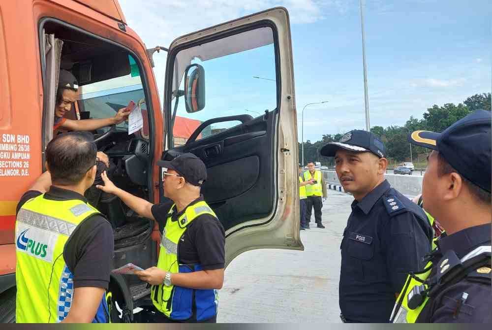 Mohd Yusof memberi risalah larangan pergerakan kepada salah seorang pemandu kenderaan berat di R&R Dengkil Arah Utara, Selangor pada Rabu.