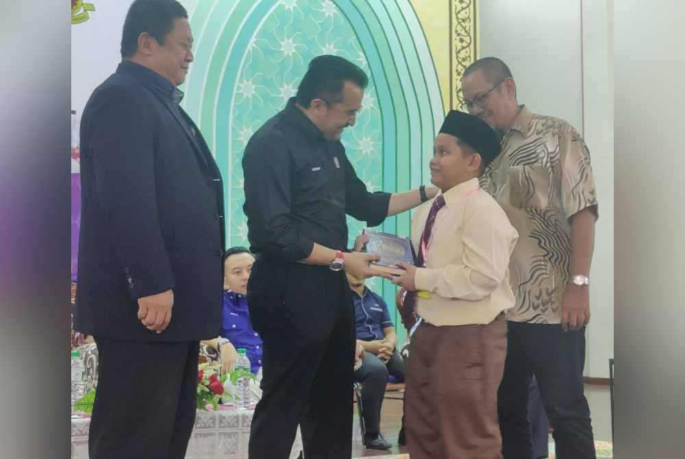 Asyraf Wajdi (dua dari kiri) menyerahkan naskah al-Quran kepada salah seorang wakil pelajar selepas melakukan tinjauan di MRSM Sungai Besar, Sabak Bernam sempena sesi pendaftaran pelajar sesi 2025 pada Rabu.
