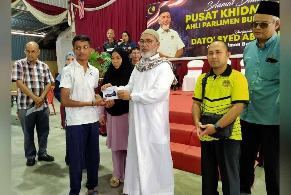 Syed Abu Hussin (tiga dari kanan) menyampaikan sumbangan kepada penerima sempena Majlis Penyampaian Bantuan Kembali Ke Sekolah di Pusat Khidmat Parlimen Bukit Gantang pada Rabu.