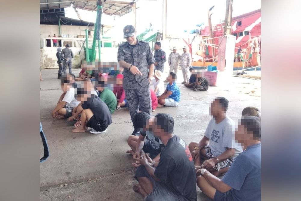 Mohamed Yusoff Khan (berdiri) bertanya sesuatu kepada Mat (duduk, kiri) yang ditahan dalam operasi pada Rabu.