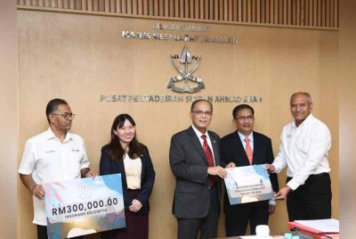 Wan Rosdy (tengah) menyerahkan bantuan perlindungan insurans berkelompok kepada wakil penggiat dan pengusaha pelancongan di Pahang dalam satu majlis pada Rabu.