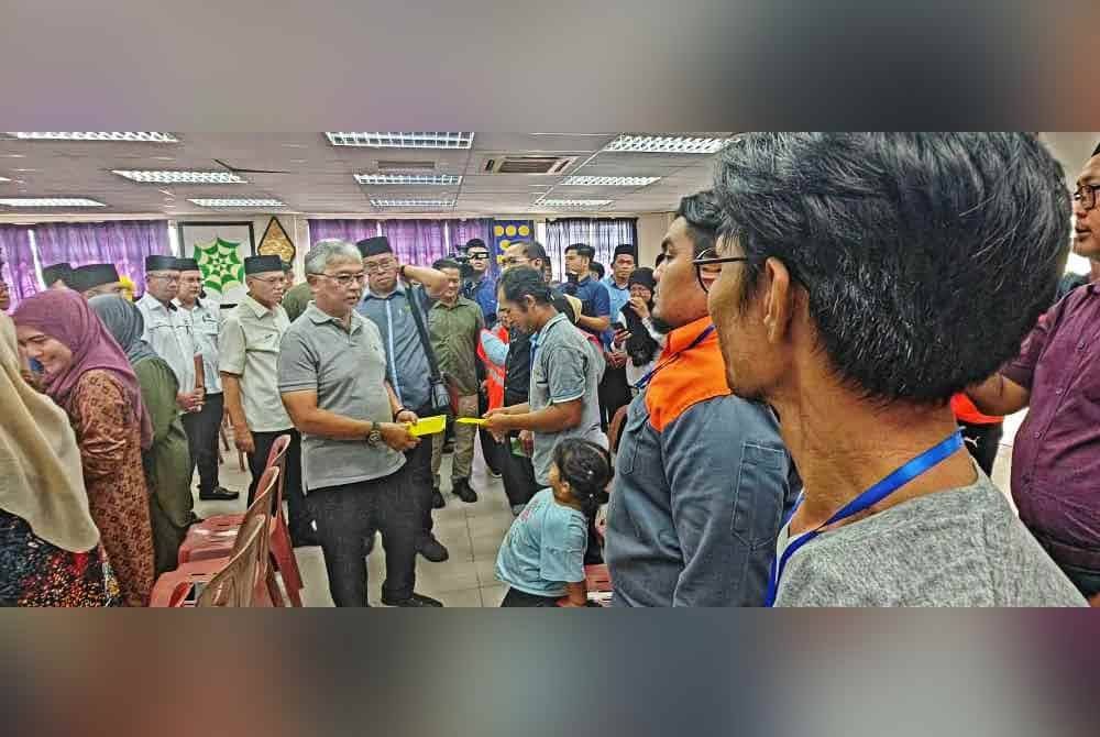 Al-Sultan Abdullah menyerahkan sumbangan kepada KIR manga banjir di PPS terbabit.