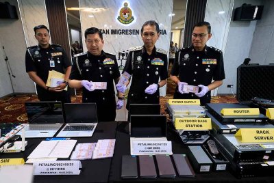 Jafri (dua kanan) menunjukan wang tunai dirampas semasa sidang media mengenai Operasi Khas berkaitan sindiket penipuan dalam talian (scammers) yang dijalankan oleh warga asing dari pelbagai negara di Jabatan Imigresen Malaysia hari ini. Foto Bernama