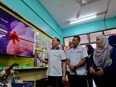 Mohd Annuar (kiri) meninjau operasi Smart TV yang ditempatkan di salah satu bilik darjah SK Raja Dihilir Ekram.