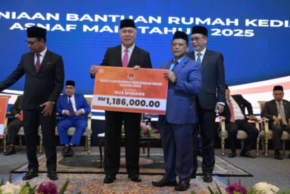 Tengku Muhamad Rizam (kiri) menyampaikan plakad Bantuan Rumah Kediaman MAIK kepada Ketua Jajahan Gua Musang, Rusydee Abdullah. 