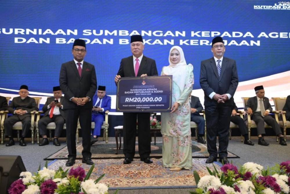 Tengku Muhamad Rizam menyampaikan plakad kepada wakil badan pertubuhan dan agensi yang menerima bantuan zakat.