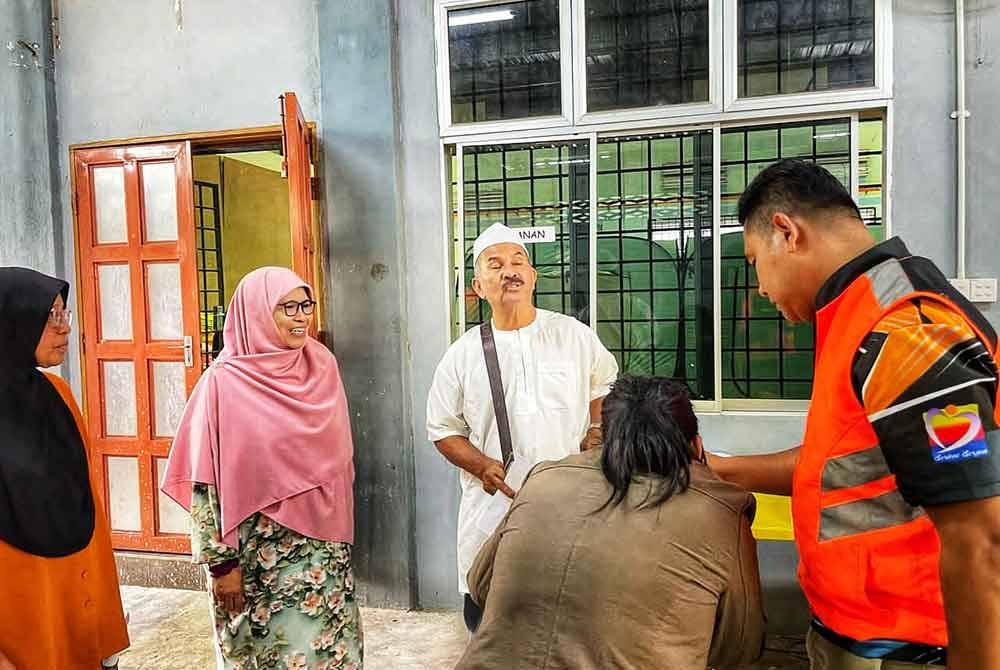 Mohd Marizie (tiga dari kiri) bersama Salamiah (dua dari kiri) ketika melawat mangsa banjir di Dewan Seri Gading pada Jumaat.