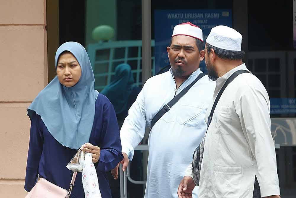 Nuraini dan Mohammad Fakhruddin (tengah) keluar dari bilik mayat Islam Jabatan Perubatan Forensik HPP selepas proses bedah siasat selesai.