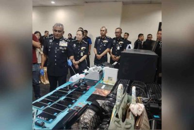 Ramli (kiri) menunjukkan pelbagai rampasan barang dalam serbuan pusat panggilan di unit kondominium di ibu negara.