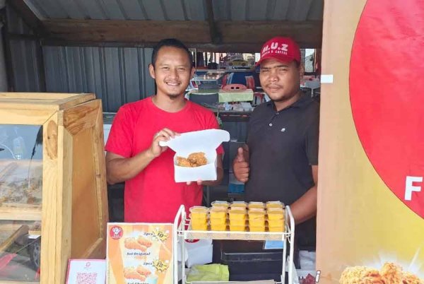 Alang (kiri) menunjukkan ayam goreng di sebuah gerai di Tanjung Lumpur. Foto Sinar Harian.