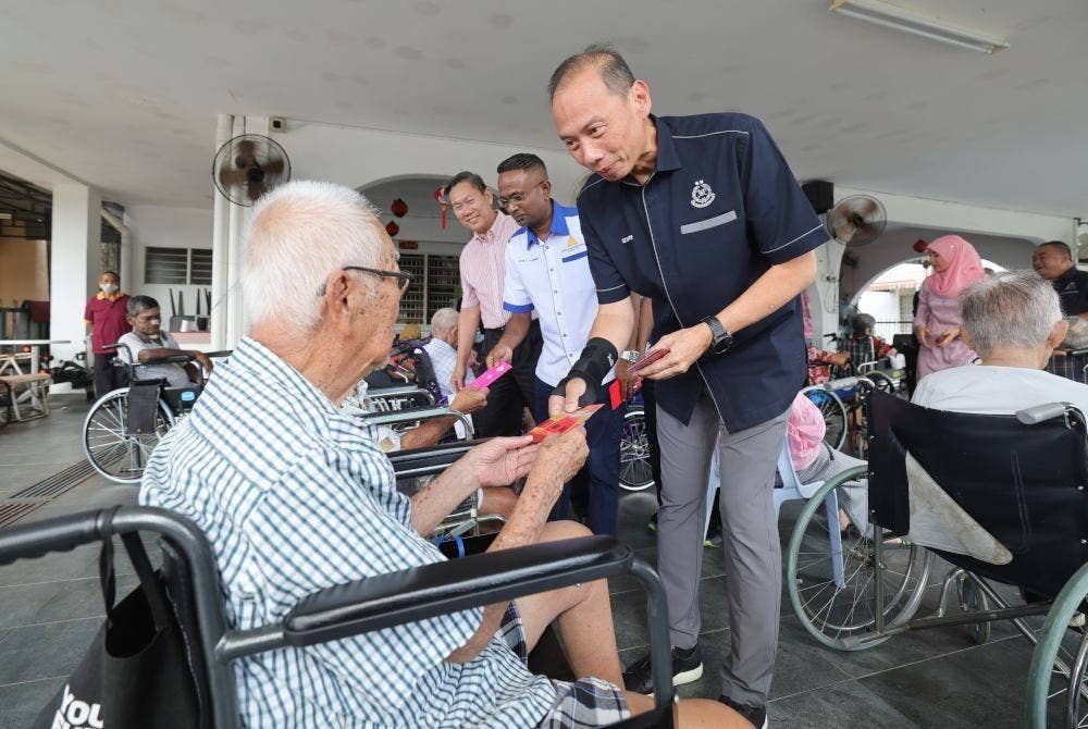 Ahmad Dzaffir (kanan) menyampaikan sumbangan angpau kepada warga emas pada Program Lawatan ke Pusat Penjagaan Orang Tua sempena Tahun Baharu Cina di Pusat Jagaan House of Megaways hari ini. Foto Bernama
