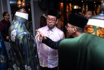 Zulkifli (kiri) mendengar penerangan mengenai Batik Nusa Malaysia dan Malaysia Madani daripada Pemilik Seni Masyaq, Ahmad Abdul Hadi Shamsul (kanan) semasa pelancaran Koleksi Kaligrafi Batik Jawi oleh Indah Atelier hari ini. Foto Bernama