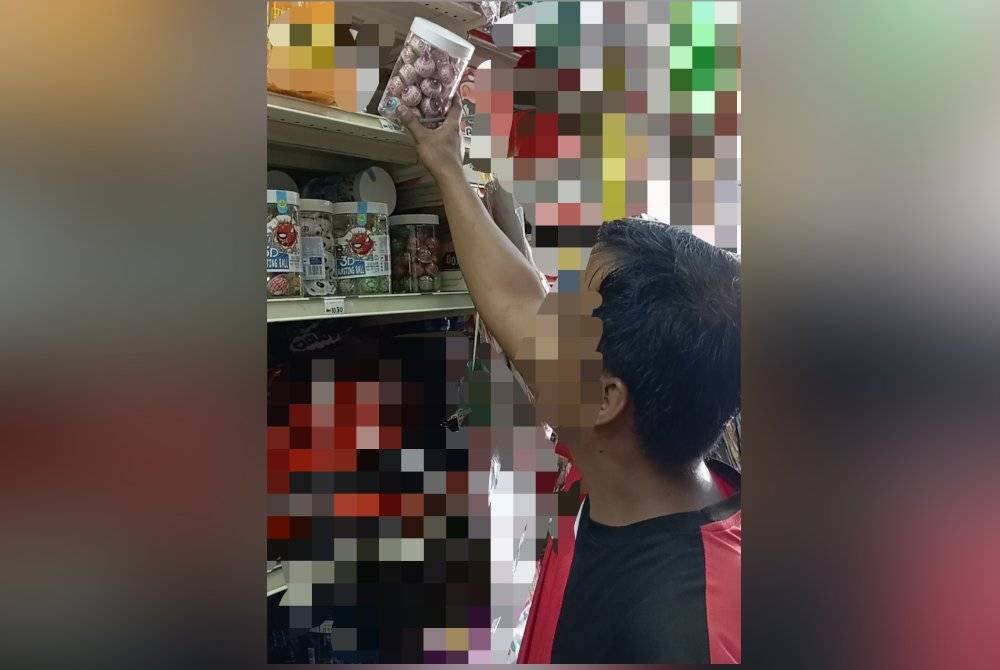 Seorang pekerja kedai menurunkan gummy berbentuk bebola mata berikutan larangan penjualan produk itu oleh KKM.