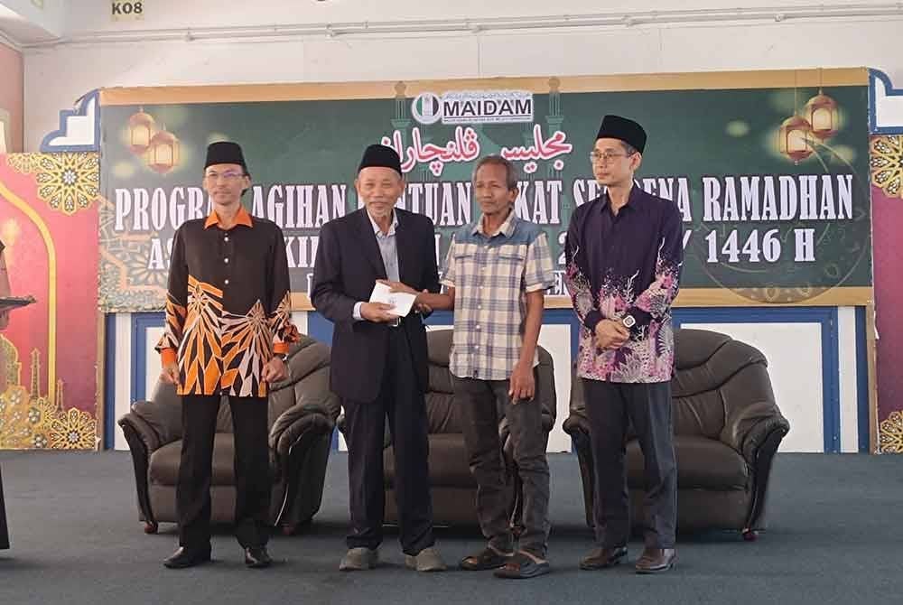 Shaikh Harun (dua dari kiri) menyampaikan sumbangan pada salah seorang asnaf