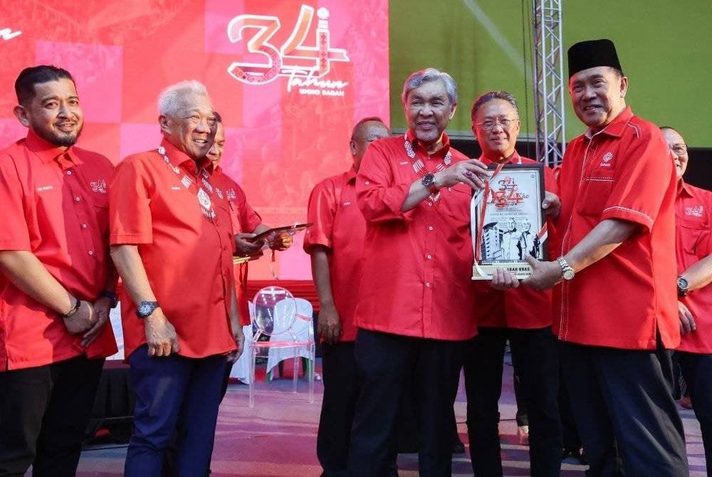 Ahmad Zahid (tiga dari kiri) menyampaikan sijil penghargaan kepada veteran UMNO Sabah selepas menyampaikan amanat pada majlis sambutan ulang tahun UMNO Sabah Ke-34 di Kompleks Sukan Tawau hari ini. Foto Bernama