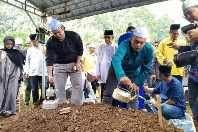 Anak sulung Allahyarham, Muhammad Iszul Imadi, 32, menyiram pusara Ishsam di Tanah Perkuburan Islam Rapat Setia di sini pada Ahad.