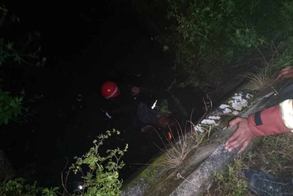 Anggota bomba menjalankan kerja mengeluarkan mangsa yang terhumban dalam parit dalam kemalangan di Jalan Batu Belah, di sini pada Isnin.