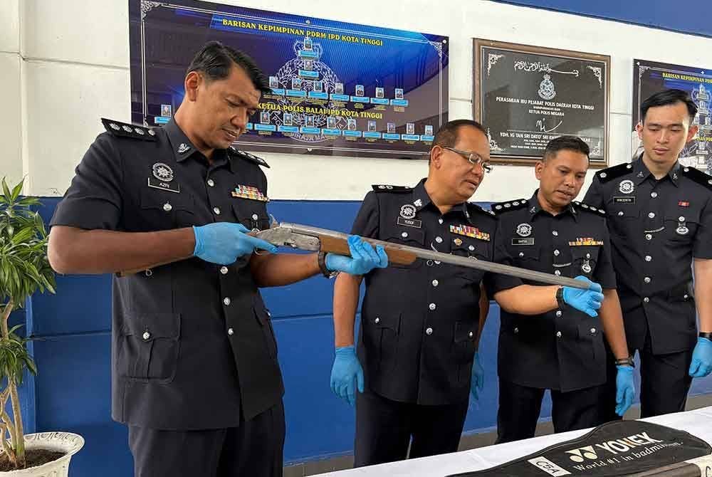 Yusof (dua dari kiri) meneliti senapang patah tunggal yang dirampas dalam serbuan berkenaan.