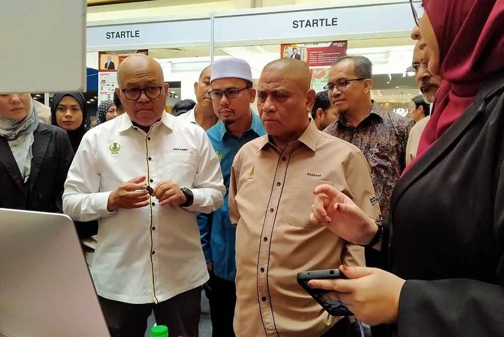 Saarani (kanan) mendengar taklimat daripada peserta ketika melawat reruai sempena Majlis Perasmian Penutup STARTLE yang diadakan di Pasar raya Besar Mydin Meru Raya di Ipoh pada Isnin.