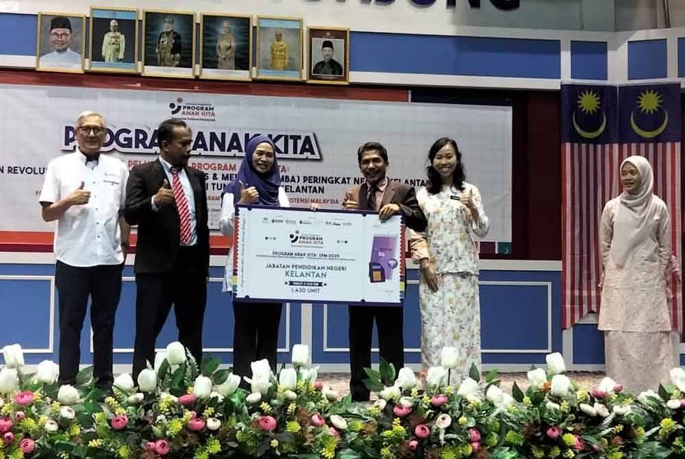 Nooraini (Tengah) menyampaikan plakad penerimaan tablet kepada Mat Lazim.