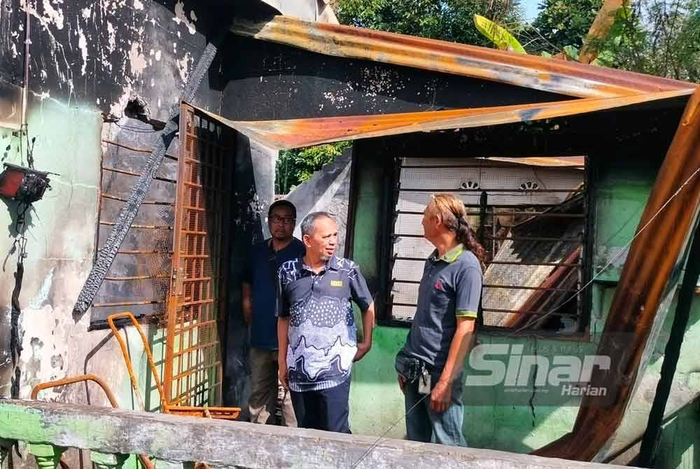 Razak (kiri) ketika melihat kesan kemusnahan kebakaran rumah yang didiami oleh Amir dan keluarganya.
Foto Sinar Harian