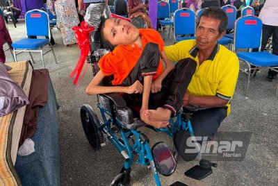 Mohamad Hakimi (kiri) yang asalnya dari kanak-kanak normal tetapi membesar dalam keadaan menghidap penyakit tulang belakang.