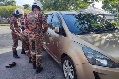 Anggota bomba ketika membuka pintu kenderaan tersebut dengan menggunakan peralatan khas. - Foto BBP Mersing