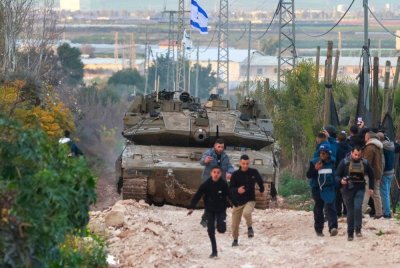 Kanak-kanak Palestin dan wartawan bertempiaran menyelamatkan diri ketika kereta kebal Israel memasuki kem pelarian Jenin di Tebing Barat yang diduduki pada Sabtu. Foto AFP