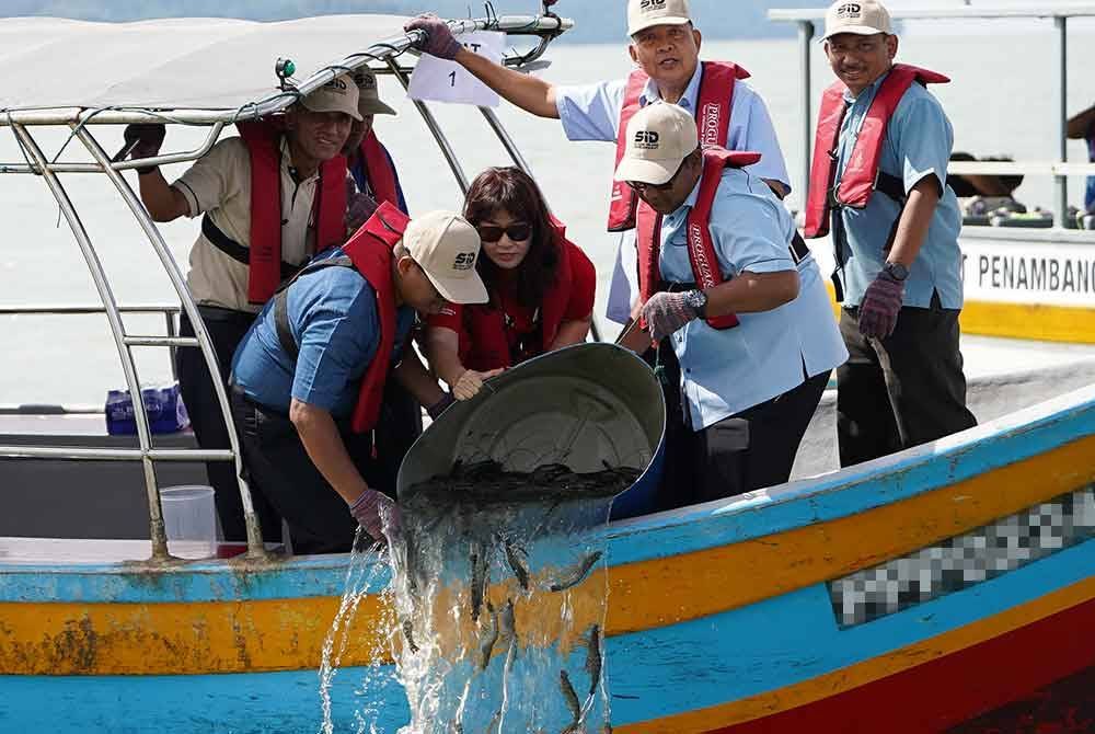 Farizan (dua dari kanan) menyaksikan pelepas udang harimau yang dibuat di perairan selatan Pulau Pinang, pada Isnin lalu.