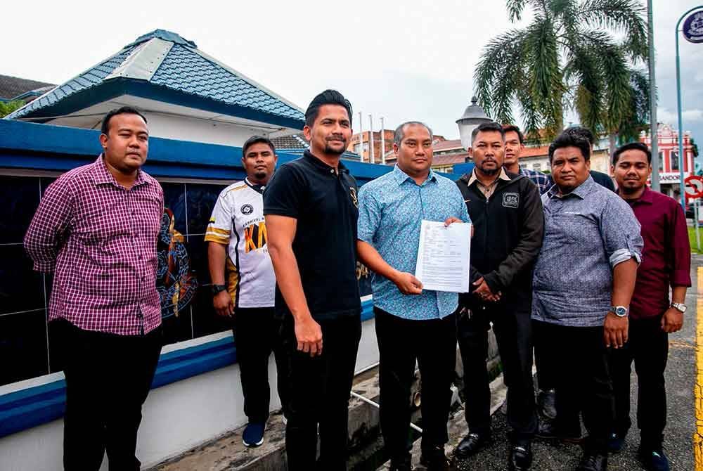 Nazirul (tengah) menunjukkan laporan polis yang dibuat ke atas seorang individu dipercayai aktivis sebuah parti politik yang mengeluarkan komen jelik dan berbaur fitnah terhadap Saarani di IPD Ipoh pada Rabu.