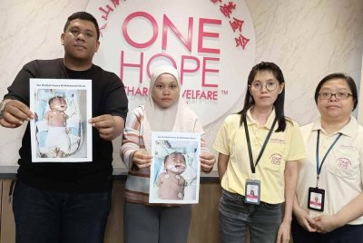 Mohammad Shahrin (kanan) dan isterinya, Nor Fazliana (dua dari kiri) menunjukkan foto anak mereka ketika hadir mendapatkan bantuan, baru-baru ini.