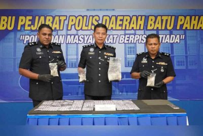 Shahrulanuar (tengah) menunjukkan dadah yang dirampas selepas serbuan di Jalan Parit Botak, Senggarang, Batu Pahat.
