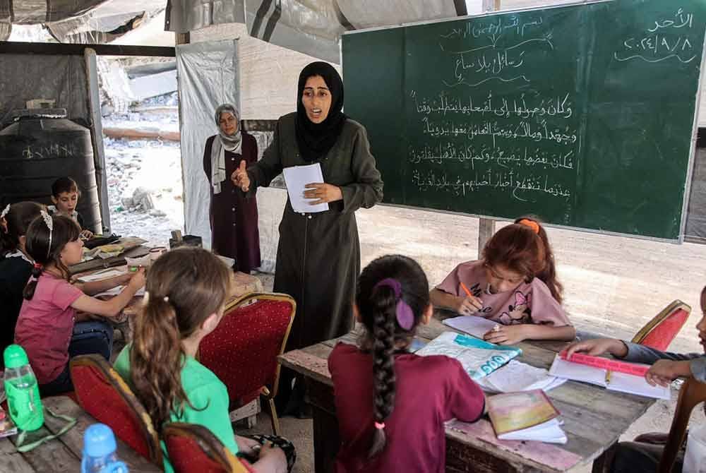 Kanak-kanak menghadiri kelas tatabahasa Arab di dalam khemah yang digunakan sebagai pusat pendidikan untuk murid sekolah rendah di Jabalia, utara Semenanjung Gaza. - Foto: AFP