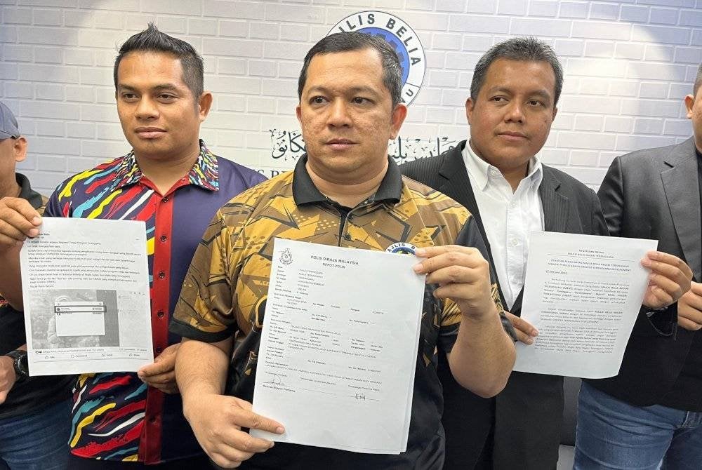 Anas Hazizul (tengah) memegang laporan polis dibuat sebelum ini berhubung hantaran media sosial yang mengaitkan dirinya dan MBNT antara pengendali sebuah akaun Facebook palsu.