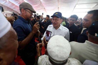 Anwar (tengah) beramah mesra dengan para petani pada Peluncuran Projek Pembangunan Infrastruktur bagi menyokong Program Penanaman Padi Lima Musim dalam tempoh dua tahun di Kampung Pida 4 dekat Ayer Hitam hari ini. - Foto: Bernama