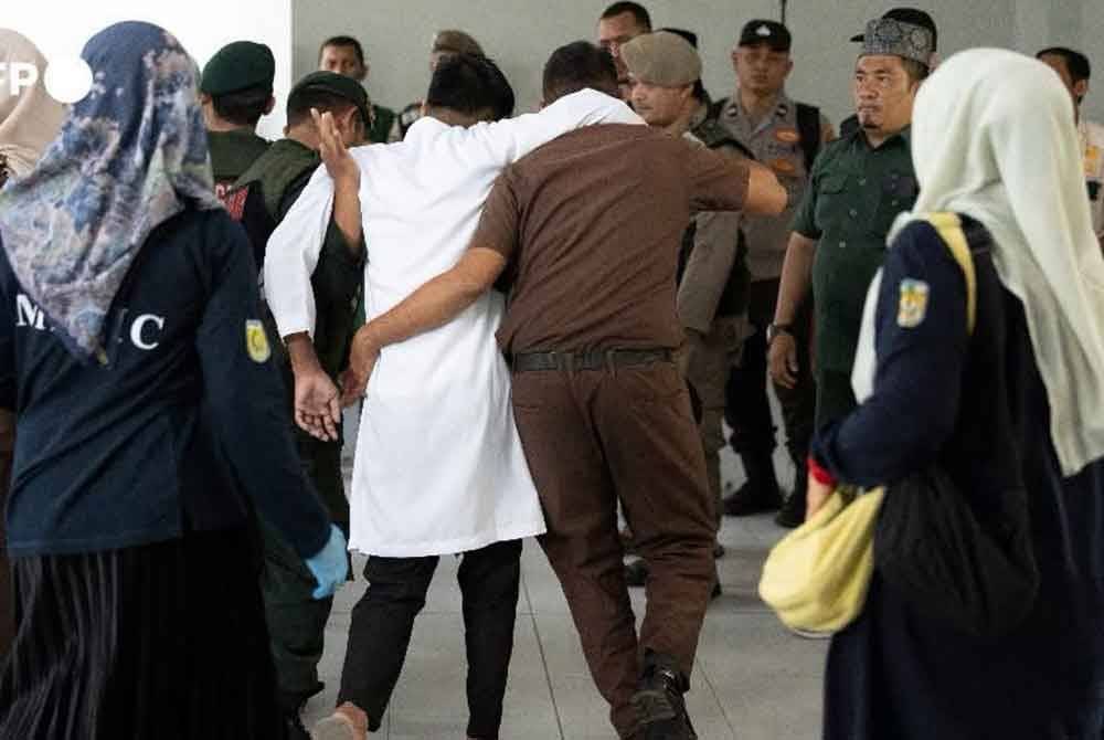 Pesalah dipapah penguat kuasa selepas selesai menjalani sesi sebat. Foto AFP