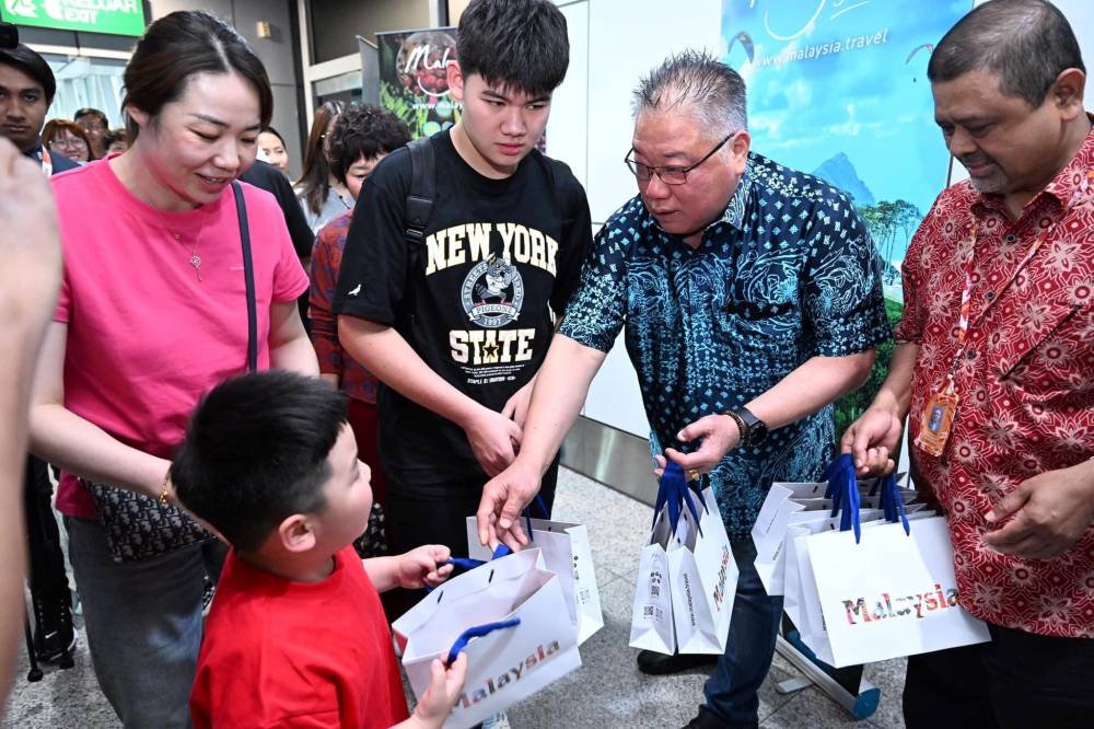 King Sing (dua dari kanan) menyantuni pelancong yang tiba di Malaysia.