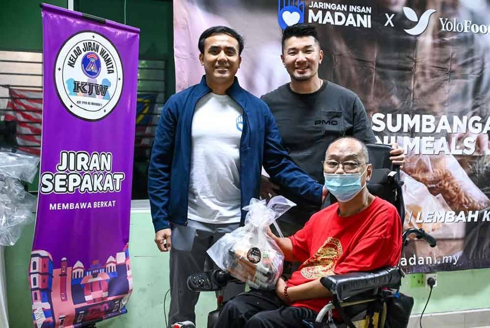 Aidi (kiri) dan Feixiang mengagihkan sumbangan Madani Meals kepada golongan memerlukan.