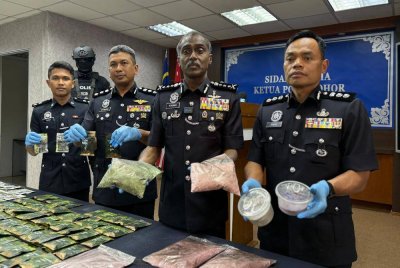 Kumar (dua dari kanan) menunjukkan bungkusan dadah yang dirampas dalam serbuan itu.