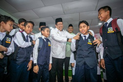 Sirajuddin (tengah) beramah mesra bersama murid-murid selepas Penyampaian Sumbangan Infak Back To School sempena Majlis Pelancaran Kampung Angkat MADANI di Sekolah Kebangsaan Menora, Kampung Menora, pada Jumaat. Foto Bernama